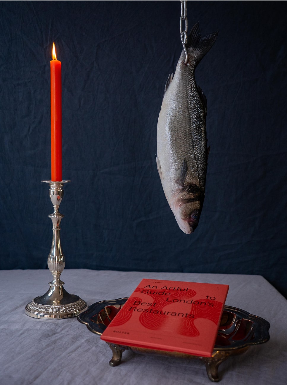 Artful still life with candle, fish, and book